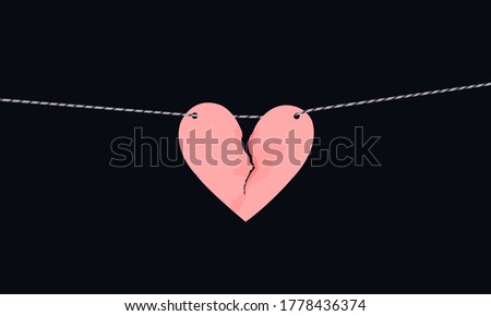 Pink heart shaped paper with torn marks hanging on the rope. Broken heart,unrequited love.