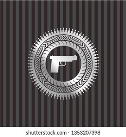 pistol icon inside silver badge or emblem