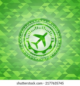 icono de plano dentro del emblema verde con fondo de mosaico triangular. 