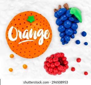 Plasticine modeling fruits orange, grapes, raspberries, cobbled together on a white background