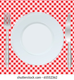 Plate, fork and spoon on red square tablecloth