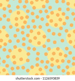 Polka dot seamless pattern with grunge shapes. Fashion circles in yellow and orange colors on mint green background. Usable as print for textile, cover, wrapping paper etc.
