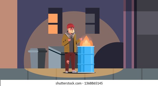 Poor Bearded Man Warming His Hands By Fire Beggar Guy Standing Near Burning Garbage In Barrel Homeless Jobless Concept Trash Can City Night Street Background Full Length