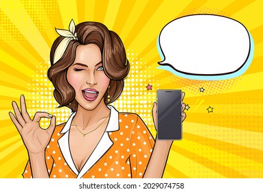 Pop art girl holding mobile phone. Winking woman showing screen of new smartphone and OK sign. Pretty lady on yellow background with empty speech bubble. Vector illustration for digital advertisement.