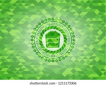 popcorn icon inside green emblem with triangle mosaic background