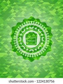 popcorn icon inside green emblem with mosaic background