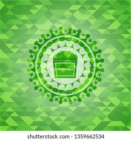 popcorn icon inside green emblem with mosaic background