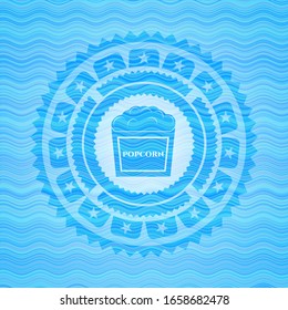 popcorn icon inside sky blue water emblem.