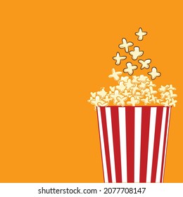 Popcorn in red and white striped cardboard bucket, Popcorn viewed from side isolated on yellow background, Flat lay of pop corn bowl. Top view