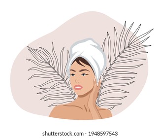 Portrait of a beautiful woman with a towel on her head touching her face or applying a cream. Skincare or spa concept