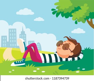 Portrait of a boy lying/resting/lies on green lawn in shade of tree in park, city outskirts. Summer.