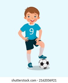 Portrait of cute little boy in sportswear posing with a soccer ball posing with hand on the waist