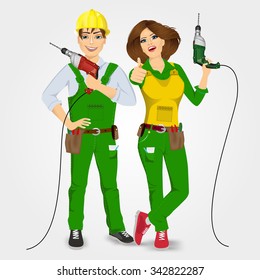 portrait of handyman and handywoman in green uniform holding drills and giving thumbs up isolated on white background