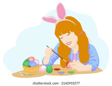 Portrait of happy girl painting Easter eggs. A german girl with red hair in a handkerchief paints eggs for Easter. Cake, willow, eggs. Happy Easter Day or preparation for Easter concept.