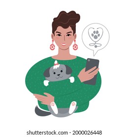 A portrait of a young caucasian woman holding up a small cute dog and a smartphone with a veterinary clinic logo in a speech bubble. Looking up animal medical services online or using a vet app on a