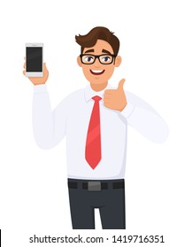 Positive Business Man Showing New Brand, Latest Smartphone. Man Holding Cell, Mobile Phone In Hand And Gesturing/making Thumbs Up Sign. Good, Like, Agree, Approve, Modern Lifestyle, Digital Technology