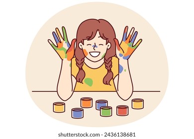 Positive girl with face and palms smeared with multi-colored paint smiles, wanting to become artist or designer. Smiling girl with gouache or watercolor on hands rejoices at school art lesson