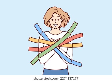 Positive girl smiles happily glued to wall with multi-colored adhesive tapes and is hostage. Metaphor of dependence and limited choice due to positive emotions and lack of critical thinking