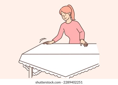 Una mujer positiva ama de casa pone una mesa con manteles blancos preparándose para la cena festiva o el almuerzo con la familia. Una feliz ama de casa con ropa informal pone manteles en la mesa después de lavarse