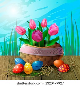 Postcard with tulips in a wicker basket and Easter eggs on a wooden table against the background of grass and sky. Beautiful greeting card or banner for Easter.