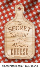 Poster with bread cutting loft wood color board lettering the secret ingredient always cheese on a red checkered tablecloth.