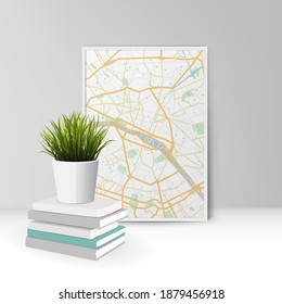 A pot of green grass stands on a pack of books near a picture with a map. Home office concept, study or freelance, working from home.