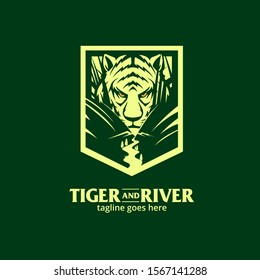 A powerful and atmospheric vector logo for "Tiger and River." The design features a detailed tiger head peering through dense jungle foliage, with its front paws framing a winding river stream that flows toward the viewer. Contained within a sharp shield crest on a dark forest green background, this light green monochromatic graphic is perfect for outdoor adventure brands, wildlife conservation groups, sports teams, and nature-themed apparel.