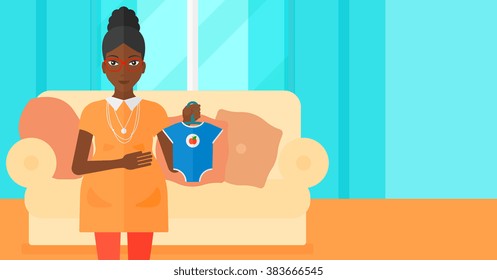 Pregnant woman with clothes for baby.