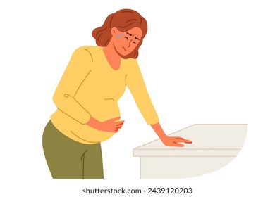 Pregnant woman holds stomach, standing near cabinet, experiencing pain due to complications caused by fetal development disorders. Pregnant girl needs hospitalization to avoid miscarriage