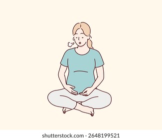 Mulher grávida praticando exercícios respiratórios. Ela se senta em uma pose de lótus e exala. A respiração ajuda a apoiar a saúde e o bem-estar durante a gravidez.