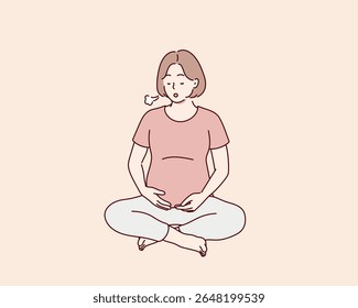 Mulher grávida praticando exercícios respiratórios. Ela se senta em uma pose de lótus e exala. A respiração ajuda a apoiar a saúde e o bem-estar durante a gravidez.