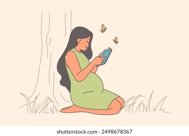 Pregnant woman reads book, sitting on lawn in park and smiles, rejoicing at imminent birth of child. Pregnant girl studies literature with recommendations on raising children and motherhood