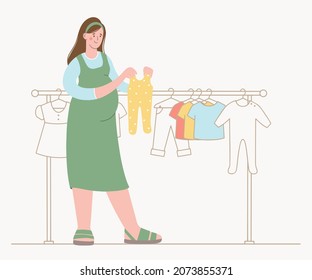 Pregnant woman is shopping for her new baby. Chooses children's clothes in  store.