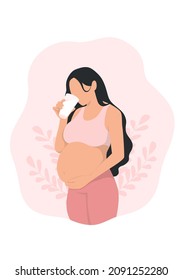 pregnant woman touching her belly and holding a glass of milk