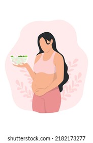 
pregnant woman touching her belly and holding holding bowl of salad
