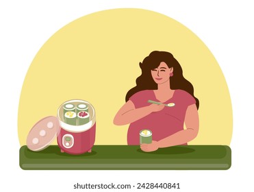 Pregnant young woman eats homemade fruit curd yogurt. A young woman sits at the table and has breakfast, next to an electric yogurt maker. Motherhood, pregnancy, healthy eating, natural vitamins. 
