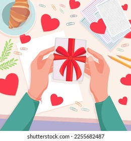 Preparing for Valentine's Day. Receiving or preparing a gift. Women's hands with a box with a red bow. Postcard or banner for Valentine's Day or Mother's Day. Top view of hands with a gift.