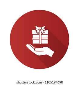 Present flat design long shadow glyph icon. Open hand with gift box. Giving, getting gift. Vector silhouette illustration