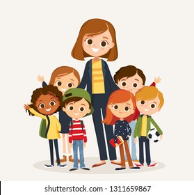 Pretty teacher standing with pupils. Classmates portrait with teacher. Elementary school.