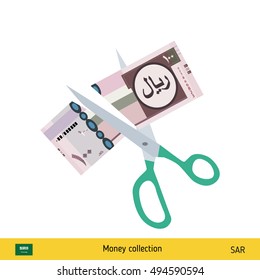 Price or cost reduction concept. Scissors cutting money bill. Saudi Arabian riyal banknote.