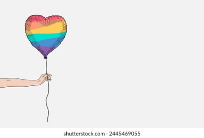 Pride month celebration concept background. Hand holding a heart shape rainbow balloon. Copy space