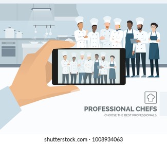 Professional chefs posing in the restaurant kitchen, a man is taking a picture using a smartphone, subjective point of view