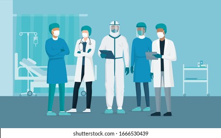 Professional doctors and nurses posing together in a hospital ward and wearing protective suits, virus outbreak emergency concept
