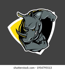 A professional flat vector mascot logo featuring a powerful ramming rhino character. The design depicts a muscular grey rhinoceros with a sharp horn and aggressive expression, shown flexing a massive bicep. Set against a dynamic yellow and black shield background with a clean white stroke outline, this high impact emblem is ideal for esports teams, gym branding, security firms, and rugged sports apparel.