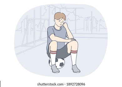 Professional football player, soccer ball, sport concept. Young unhappy boy football player sitting on soccer ball and feeling sad after failure during workout or game. Sport, athletics, team sport 