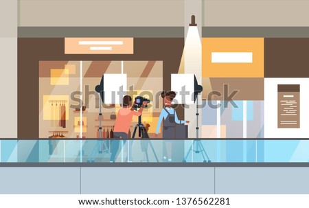 professional man photographer using dslr camera on tripod shooting african woman model girl posing in modern shoping mall supermarket interior horizontal full length