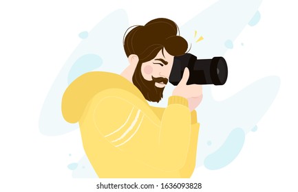 Professional photographer with camera taking photo isolated on white. Young bearded man looking for a good frame view.
