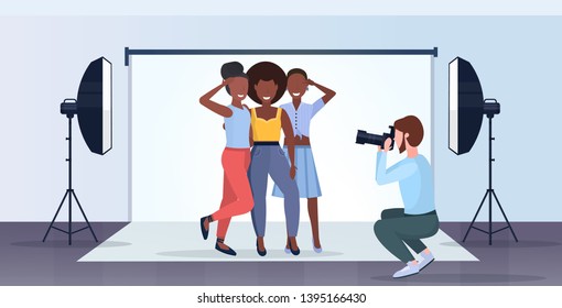 professional photographer using camera man shooting beautiful sexy african american women models posing modern photo studio interior horizontal full length