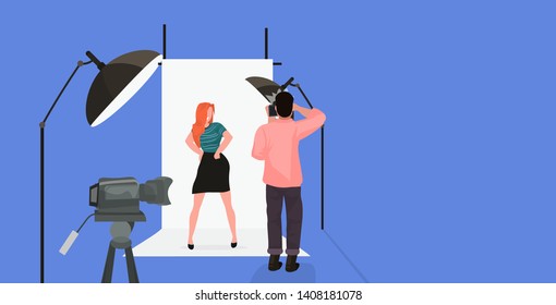professional photographer using camera man shooting beautiful sexy redhead woman model posing in modern photo studio horizontal full length flat