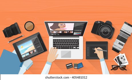 Professional photographer working at office desk, he is editing his pictures using a laptop and a graphic tablet